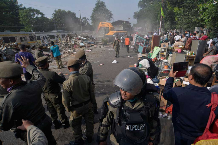 Satpol PP berjaga di dekat bangunan permukiman warga yang ditertibkan.
