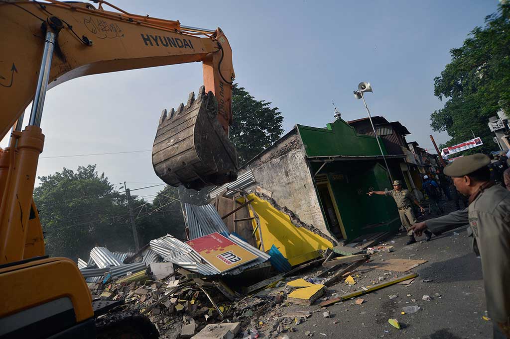 Satpol PP dengan menggunakan eskavator merobohkan bangunan permukiman warga.