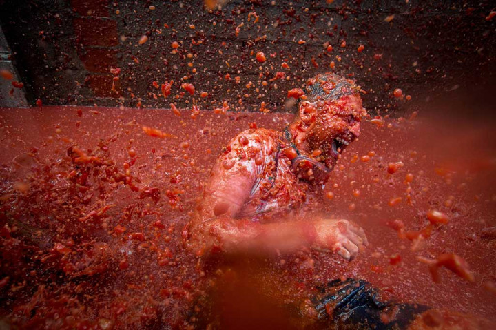 Seorang peserta tertawa riang saat mandi di genangan bubur tomat.