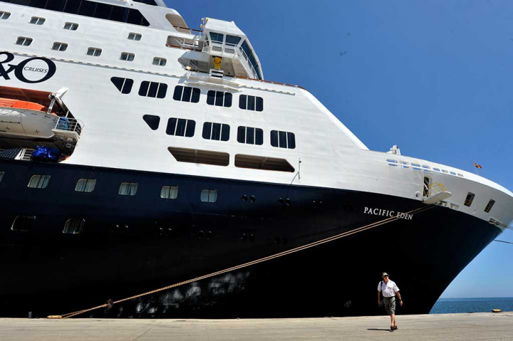Turis melintas di dekat kapal pesiar Pacific Eden saat berlabuh di Pelabuhan Sukarno-Hatta Makassar, Sulawesi Selatan.