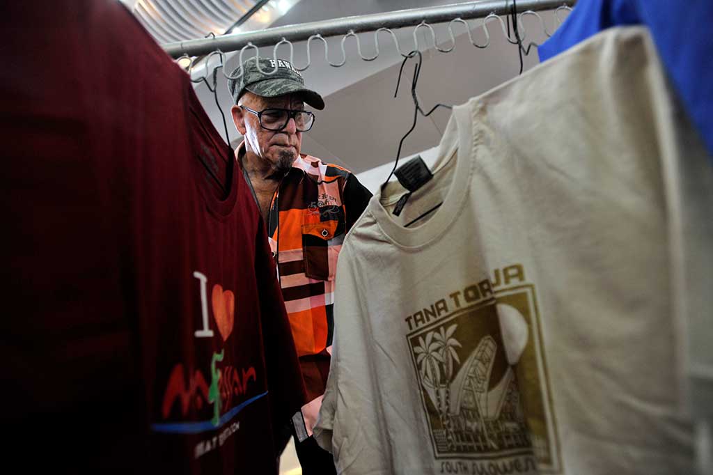 Seorang turis penumpang kapal pesiar Pacific Eden memilih baju khas Sulsel di Pelabuhan Sukarno-Hatta Makassar.