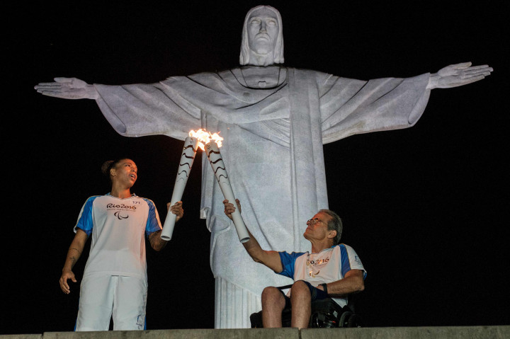Pejudoka Brasil Rafaela Silva menerima api Olimpiade dari penulis Thomas Magalhaes tanda dibukanya Paralympic 2016. Upacara pembukaan berlangsung di depan patung Kristus Penebus di puncak Gunung Corcovado di Rio de Janeiro. AFP PHOTO / Yasuyoshi CHIBA