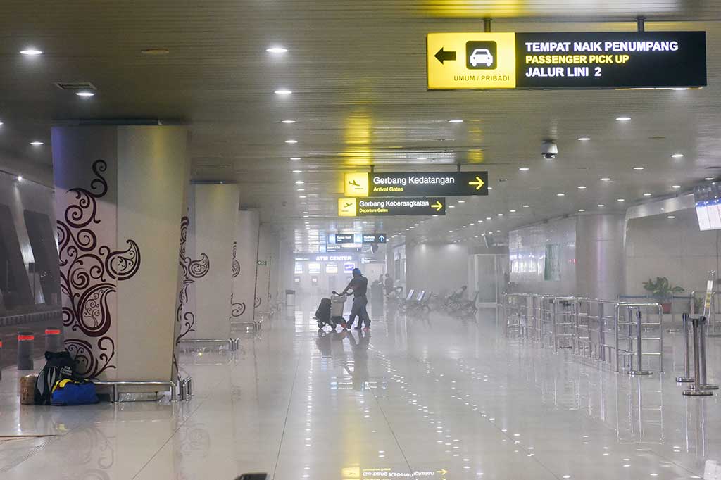 Penumpang melintas saat petugas melakukan pengasapan.