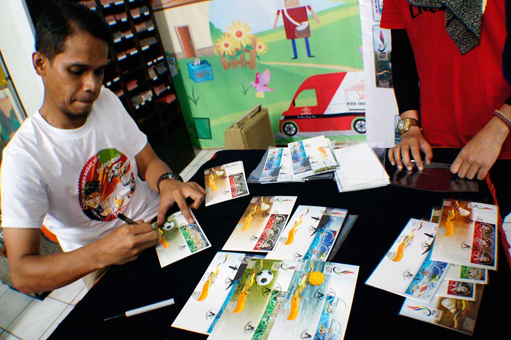 Desainer Prangko PON XIX Anwar Firdaus menandatangani kartu pos seri PON XIX di kantor Pos Besar Bandung, Jawa Barat, Jumat (9/9/2016).