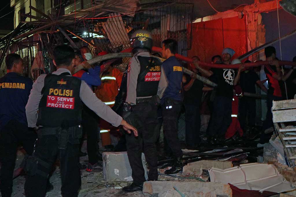 Petugas pemadam kebakaran memadamkan api di lokasi ledakan, di Makassar, Minggu malam.