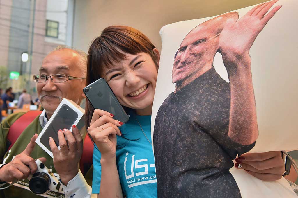 Pembeli berfoto bersama iPhone 7 dan poster pendiri Apple Steve Jobs, di Tokyo.
