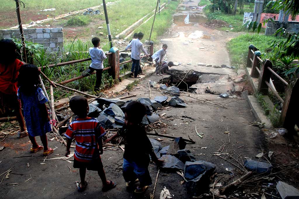 Anak-anak melihat jembatan yang ambles di Jalan Pitara, Pancoran Mas, Depok, Jawa Barat.