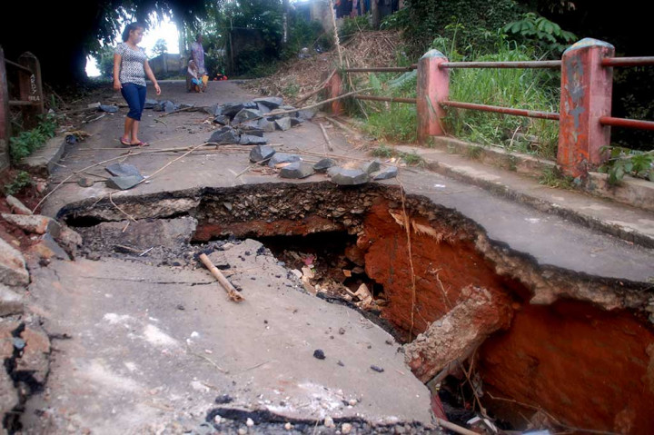 Warga melintasi jembatan yang ambles di Jalan Pitara, Pancoran Mas, Depok.