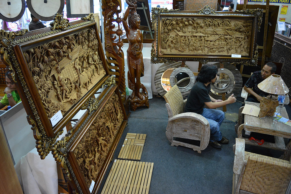 Seorang calon konsumen berbincang dengan penjaga stan kerajinan ukiran kayu.