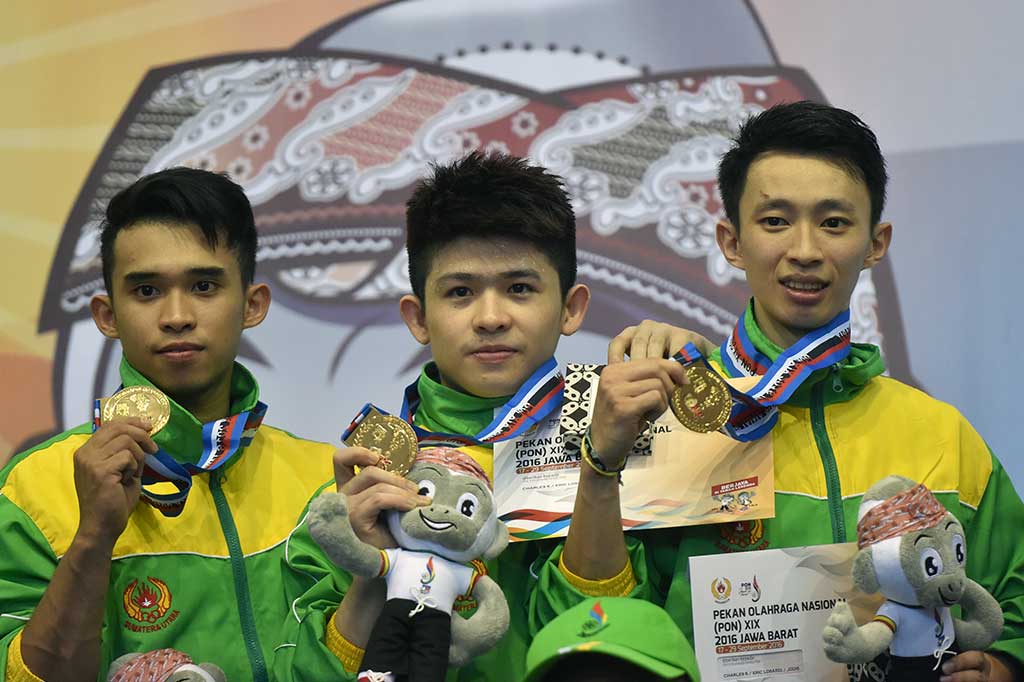 Atlet Wushu Sumut Jodis (kiri) bersama rekannya Eric Losardi (tengah) dan Charles Sutanto memperlihatkan medali emas nomor Duilian Putra PON XIX.
