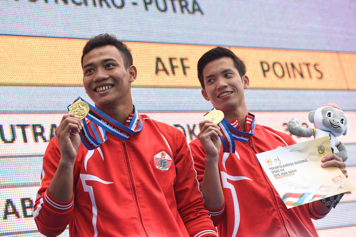 Atlet loncat indah putra DKI Jakarta Andriyan (kanan) dan Adityo Restu Putra (kiri) menunjukkan medali emas yang diraih usai final nomor Menara Synchro Putra PON XIX di Gelanggang Renang FPOK UPI Bandung, Jabar, Kamis (22/9/2016).