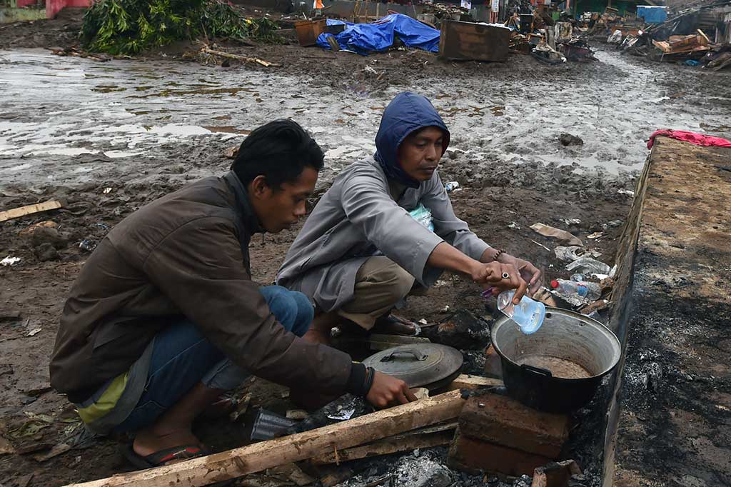 Warga memasak dengan peralatan seadanya di lokasi bangunan yang rusak akibat banjir bandang di Kampung Cimacan, Tarogong.