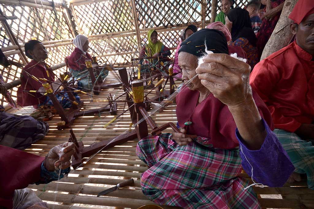 Warga lansia memintal kapas untuk menjadi benang (a'nganni) menggunakan pemintal tradisional pada rangkaian tradisi Pattakkang di Dusun Borong Rappo.