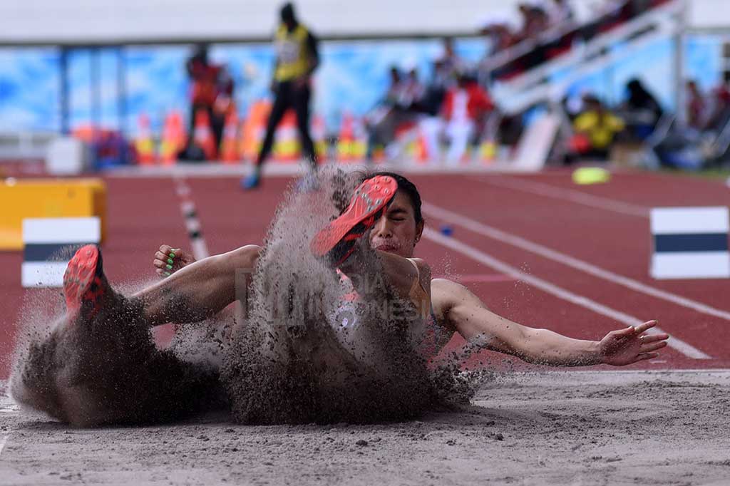 Atlet asal Bali Maria Natalia Londa menyentuh pasir pada final nomor lompat jangkit putri PON XIX di Stadion Pakansari, Cibinong, Bogor, Jawa Barat, Minggu (25/9/2016).