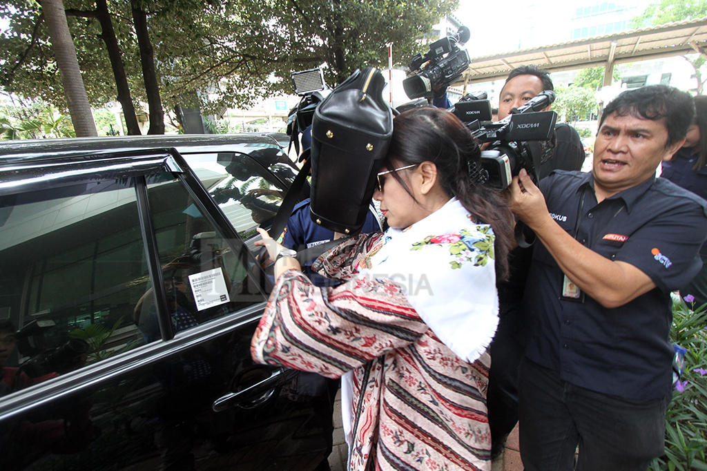 Istri Irman Gusman, Liestyana Rizal menutupi wajahnya dari sorotan kamera menggunakan tasnya.