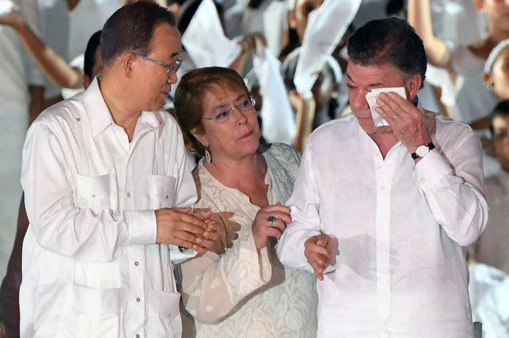 Presiden Kolombia menyeka air matanya disaksikan Ban Ki-moon (kiri) dan Presiden Chile Michelle Bachelet. 