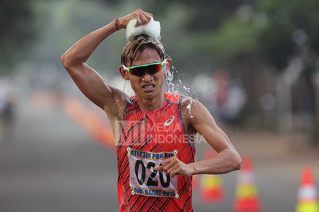 Hendro mengguyur kepala dengan air dingin saat bertanding pada final Jalan Cepat 20.000 Meter Putra.