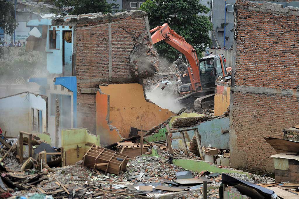 Petugas dibantu eskavator meruntuhkan rumah-rumah di pinggir Sungai Ciliwung tersebut.