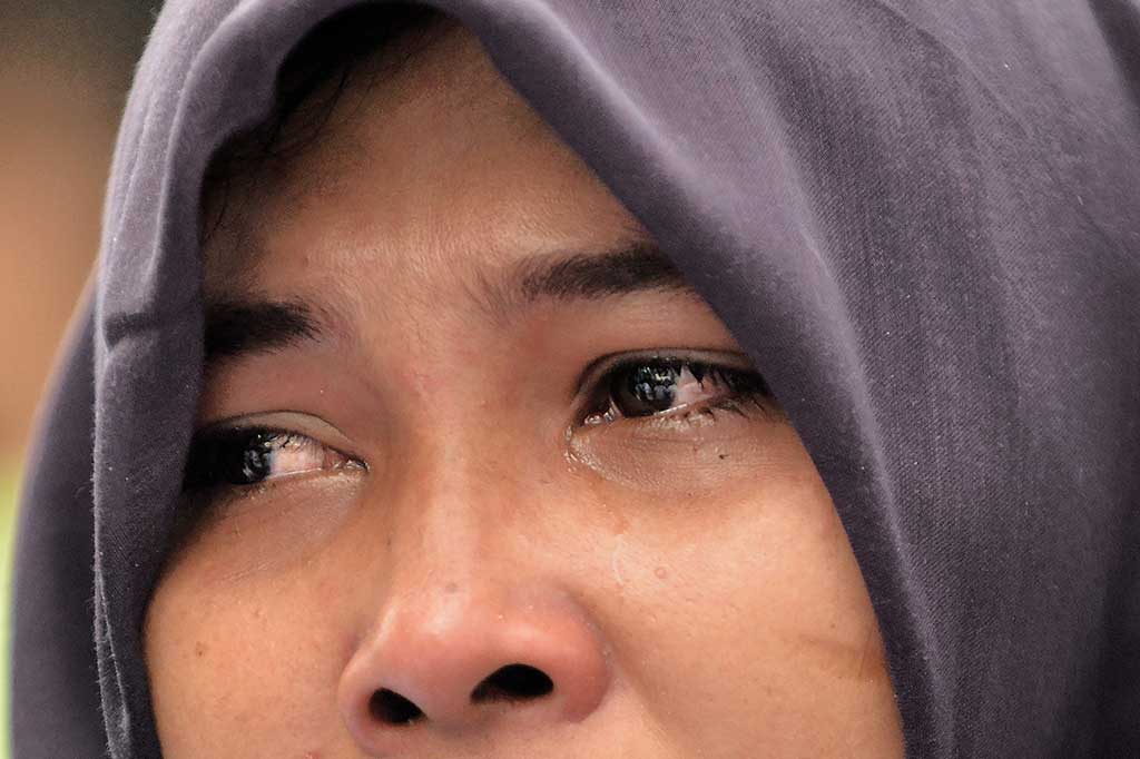 Seorang perempuan meneteskan air mata melihat rumahnya digusur.