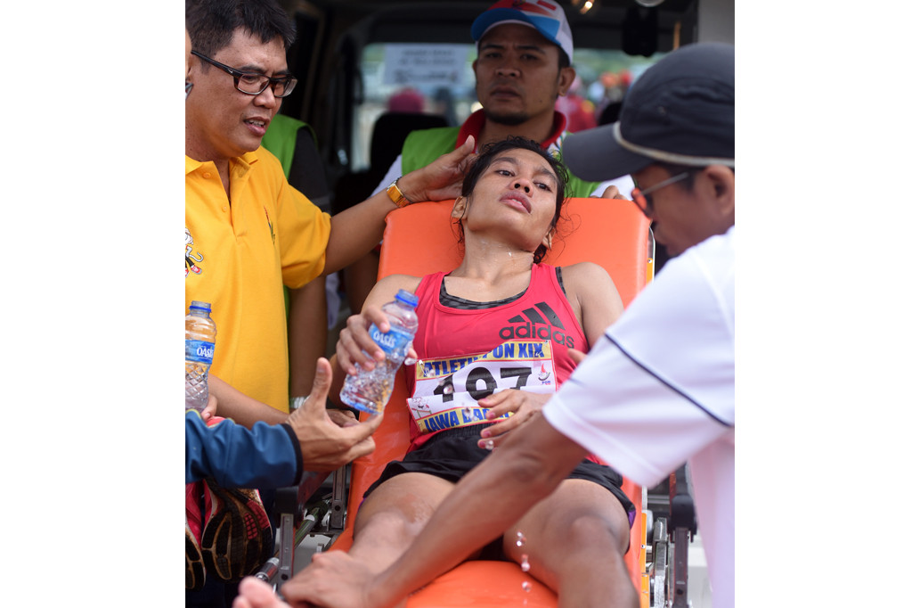 Pelari DKI Jakarta Odekta Elvina Naib (tengah) mendapatkan perawatan medis ketika lomba Lari Maraton Putri PON XIX di Cibinong, Bogor, Jawa Barat, Rabu (28/9/2016).