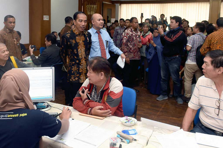 Presiden Joko Widodo melihat petugas pajak saat melayani wajib pajak yang ikut serta dalam program Pengampunan Pajak di Kantor Pelayanan Pajak Gabungan di Jalan M.I. Ridwan Rais, Jakarta.