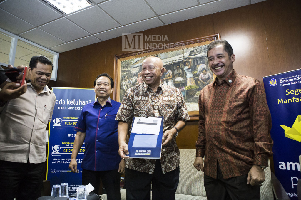 Pendiri Grup Medco Arifin Panigoro (kedua kanan) memperlihatkan berkas laporan disaksikan Kepala Kantor Wilayah Direktorat Jenderal Pajak Jakarta Selatan Sakli Anggoro (kanan) dan Wakil Ketua Asosiasi Pengusaha Indonesia (APINDO) Suryadi Sasmita (kemeja biru) usai mengikuti program tax amnesty.