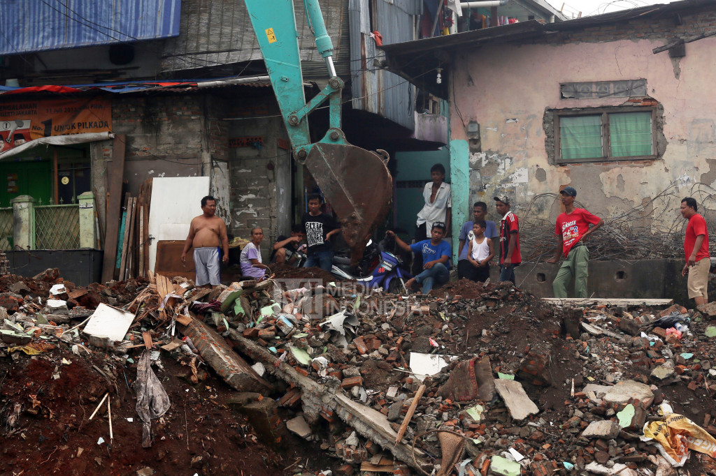 Warga melihat alat berat yang meratakan pembongkaran kawasan Bukit Duri, Jakarta.
