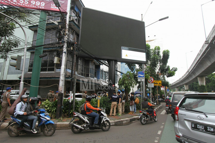 Polisi berjaga di sekitar papan billboard videotron yang menayangkan tayangan porno di Jalan Prapanca Raya, Jakarta Selatan, Jumat (30/9/2016).