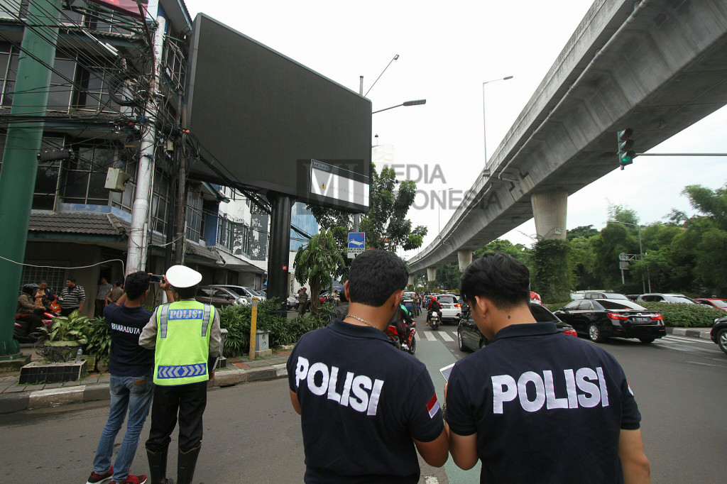 Polisi berjaga di sekitar papan billboard videotron yang menayangkan tayangan porno di Jalan Prapanca Raya, Jakarta Selatan, Jumat (30/9/2016).