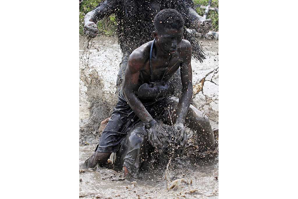 Petani yang berdandan seperti kerbau menceburkan penonton kedalam sawah berlumpur.