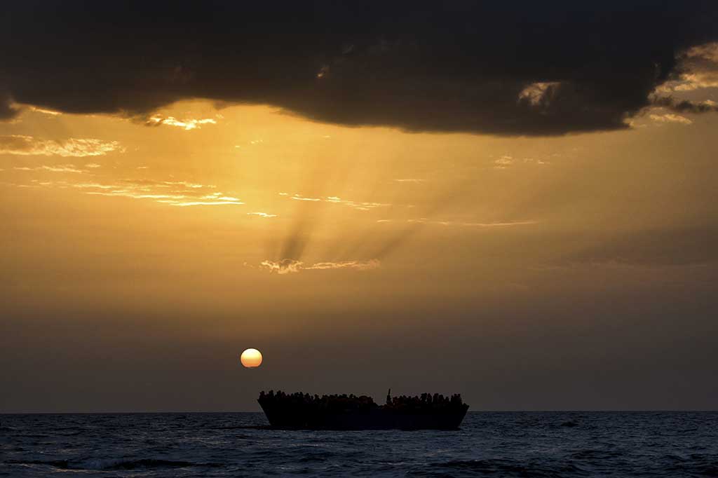 Ratusan imigran menunggu penyelamatan saat matahari terbenam di Laut Mediterania.