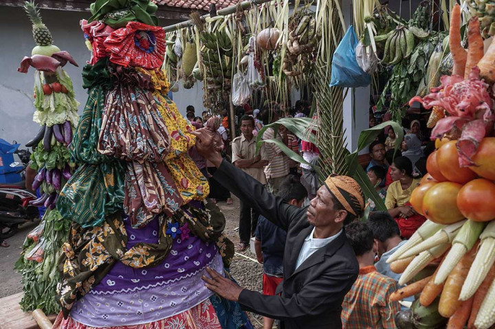 Tetua adat merapikan gunungan yang terbuat dari kain batik tradisional banyumasan.
