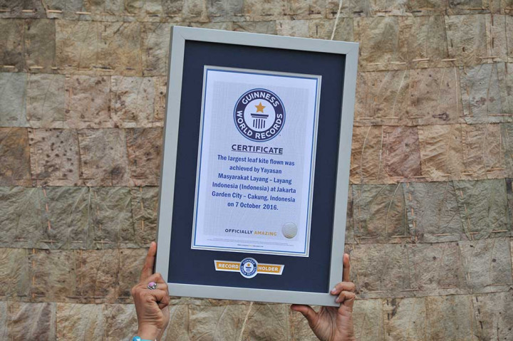 Peserta memperlihatkan piagam Guinness Book of Record layang-layang berbahan daun Kolope dalam pemecahan rekor dunia.