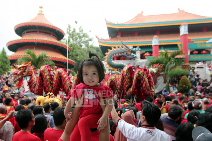 Seorang anak diangkat orangtuanya saat menyaksikan pawai peringatan hari lahir Nabi Kongzi (Zhi Sheng Dan) ke-2567 di kawasan Klenteng Kong Miao, TMII, Jakarta, Minggu (9/10/2016). 