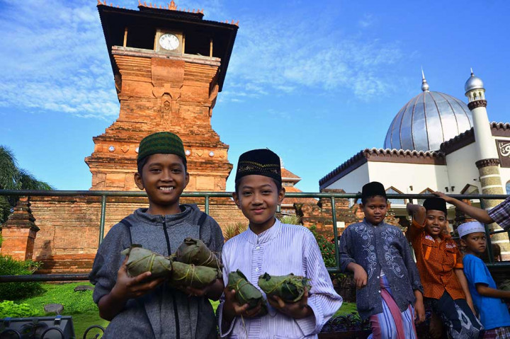 Dua anak berpose di depan Masjid Menara Kudus usai mendapatkan nasi jangkrik.