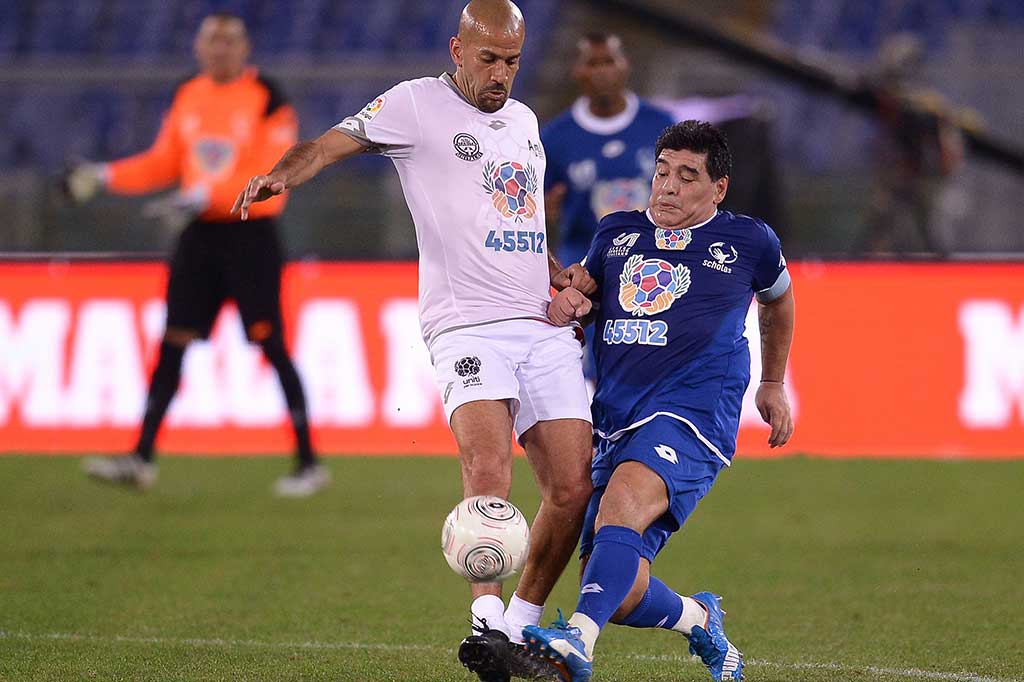 Maradona berebut bola dengan mantan anak asuhnya di timnas Argentina Juan Sebastian Veron.