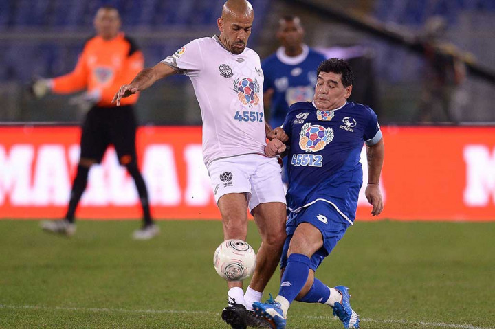 Maradona berebut bola dengan mantan anak asuhnya di timnas Argentina Juan Sebastian Veron.