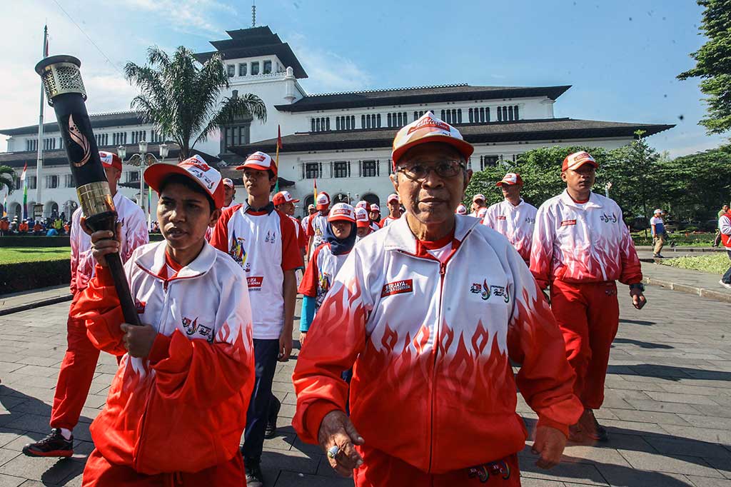Ika Damayanti dan Abdul Kholik berjalan membawa api obor Kirab Peparnas XV Jabar 2016.
