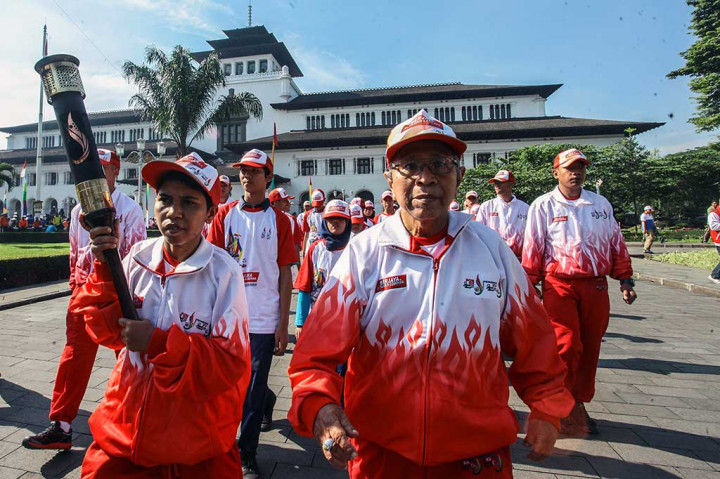 Ika Damayanti dan Abdul Kholik berjalan membawa api obor Kirab Peparnas XV Jabar 2016.