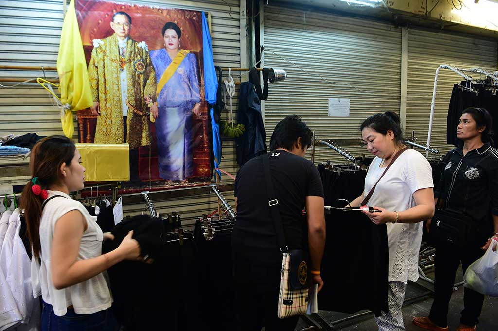 Warga memilih pakaian hitam di emperen toko di Bangkok.