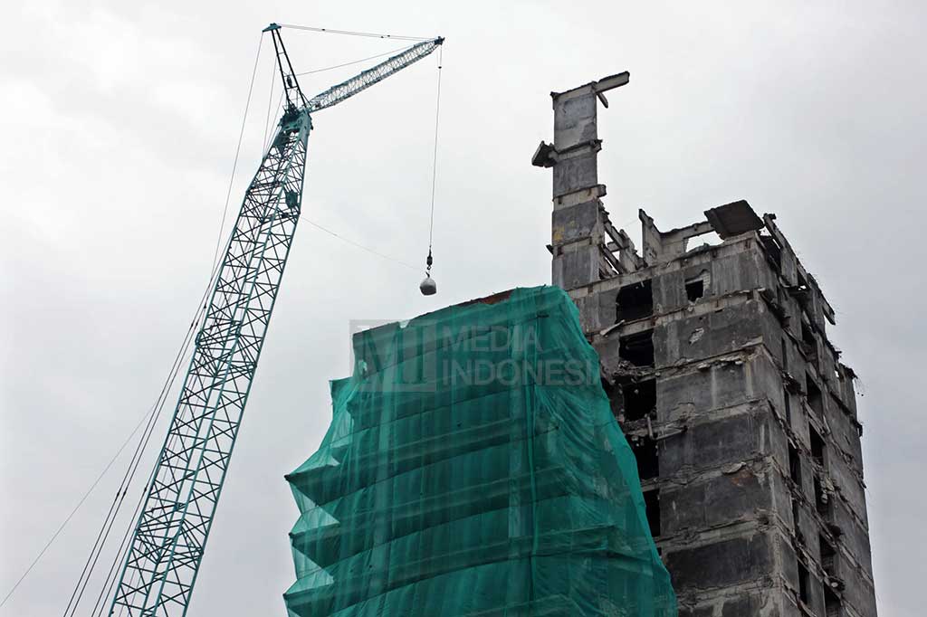 Karung berisi pasir diangkat menggunakan crane untuk diletakkan di lantai atas gedung.