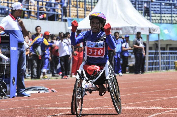 Atlet Paralimpik Balap Kursi Roda asal Kalsel Mulyani (kiri) melakukan selebrasi saat memasuki garis finis pada pertandingan atletik balap kursi roda 400 meter Peparnas XV di Stadion Gelora Bandung Lautan Api, Bandung, Minggu (16/10/2016)