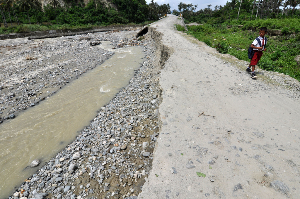 Seorang siswa SD berjalan di jalan yang ambles di Kelurahan Pantoloan Boya, Kota Palu, Sulawesi Tengah, Senin (17/10/2016)