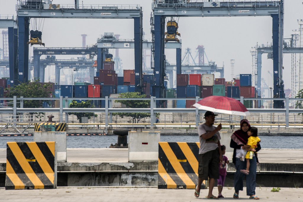 Warga berjalan dengan latar belakang suasana pelabuhan peti kemas di Pelabuhan Tanjung Priok, Jakarta, Selasa (18/10/2016)