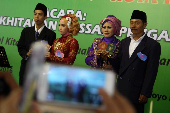 Dua pasangan pengantin berfoto sembari menunjukkan buku nikah seusai mengikuti nikah massal.