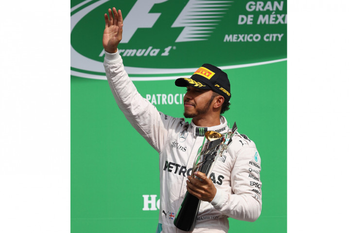 Hamilton mengangkat trofi usai menjadi yang tercepat dalam balapan yang berlangsung di Autodromo Hermanos Rodriguez, Minggu (30/10/2016)