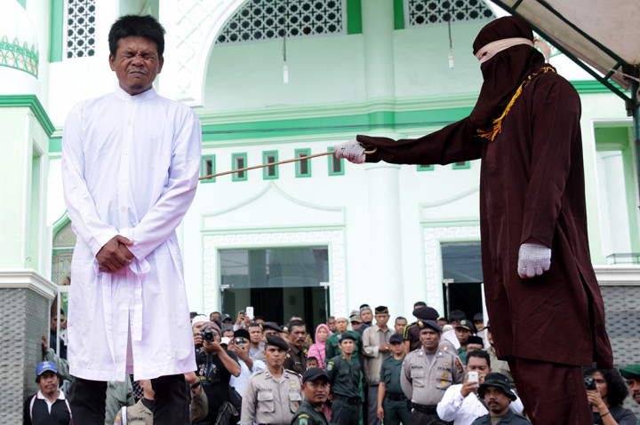 Terpidana pelanggar peraturan daerah (qanun) syariat Islam (kiri) dicambuk lima kali  di halaman masjid Peunayong, Banda Aceh, Aceh, Senin (31/10/2016)