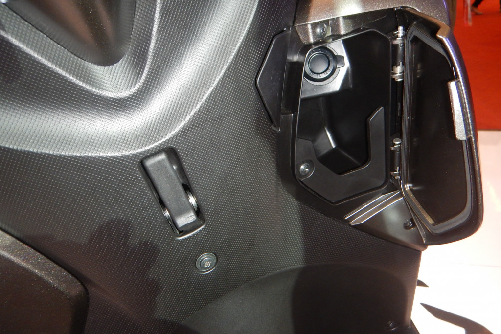 Ada laci kecil berpenutup yang dilengkapi slot charger untuk telepon selular. 