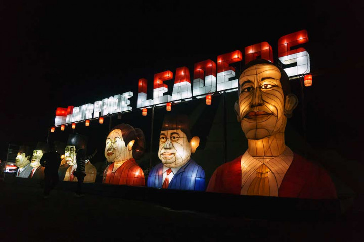 Pengunjung berfoto dengan latar belakang lampion karakter tokoh presiden Indonesia di kawasan wisata malam Taman Pelangi. 