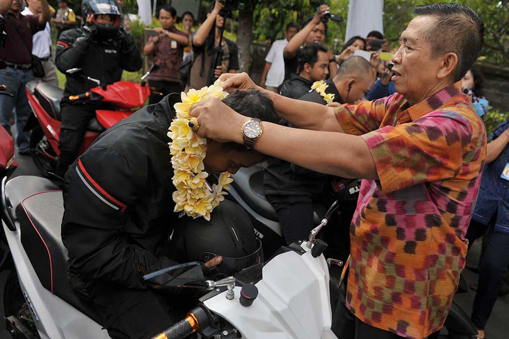 Gubernur Bali Made Mangku Pastika mengalungkan bunga kepada pengedara motor Gesits yang baru tiba di Denpasar, Bali, Sabtu.